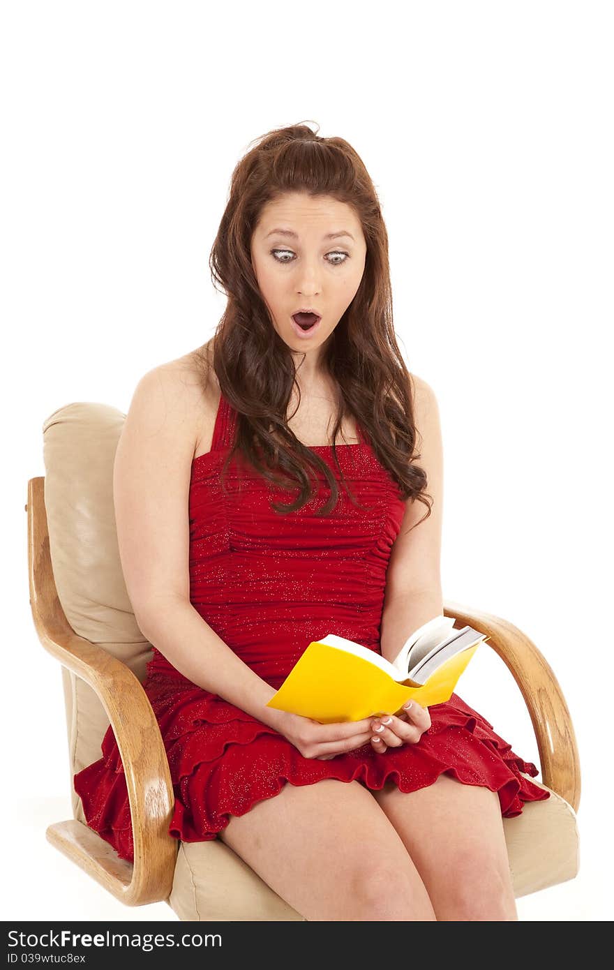 A woman in a red dress is reading a book and looks shocked. A woman in a red dress is reading a book and looks shocked.