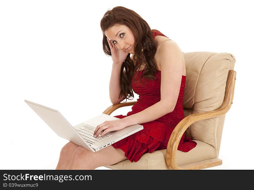 A woman with a laptop is wearing a red dress sitting in a chair. A woman with a laptop is wearing a red dress sitting in a chair.