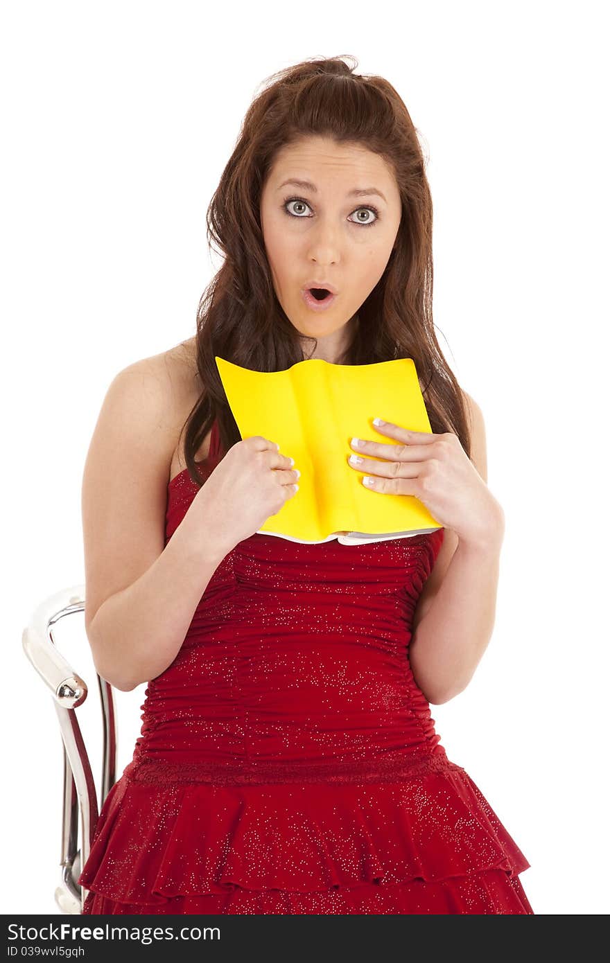 A woman in a red dress is reading a book and looks shocked. A woman in a red dress is reading a book and looks shocked.