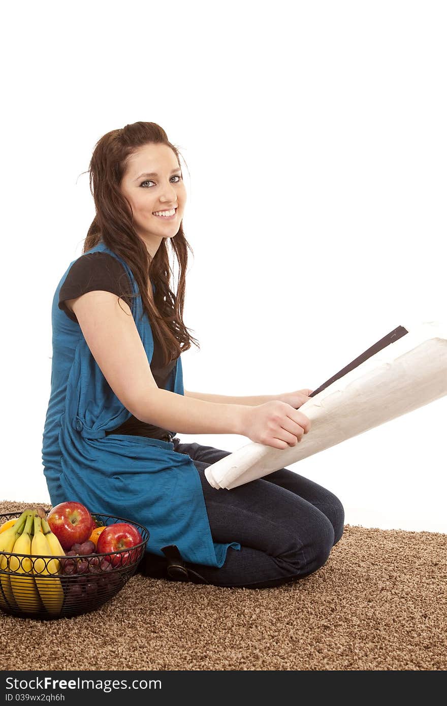 A woman is looking at plans sitting by a basket of fruit. A woman is looking at plans sitting by a basket of fruit.