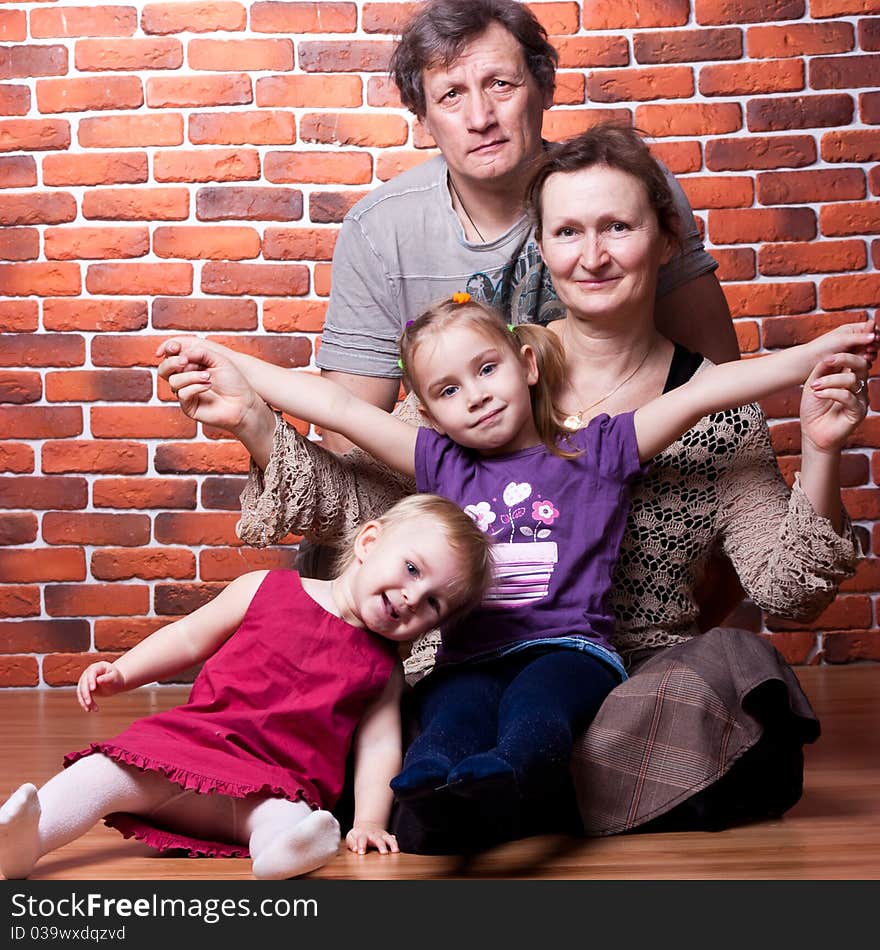 Happy seniors couple with grandchildren against brick wall