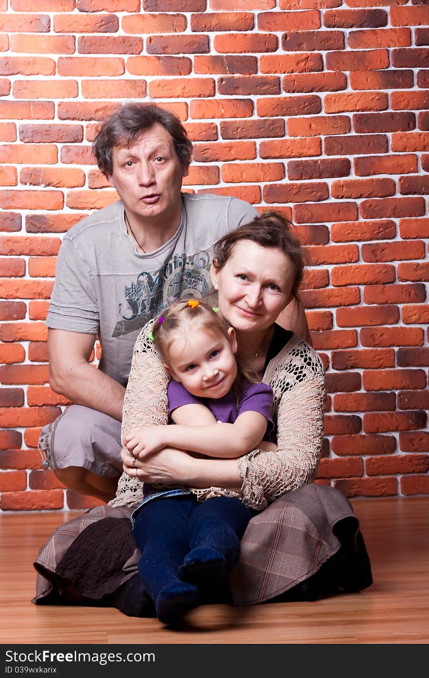 Happy seniors couple with grandchild against brick wall