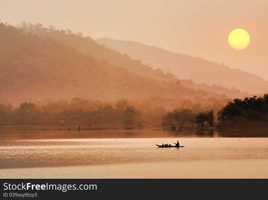 Silhouette of a fisherman in a boat on a lake in the morning