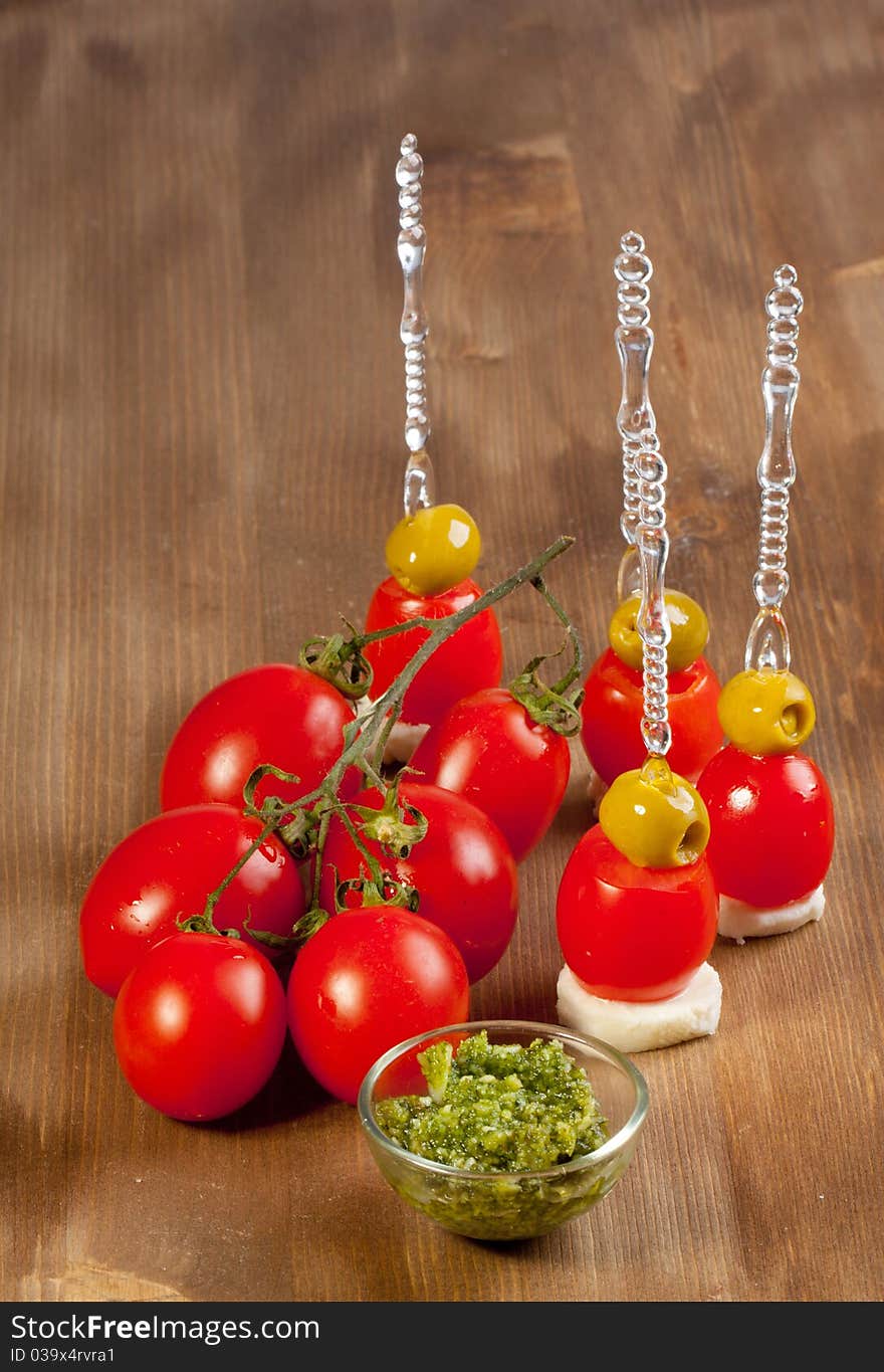 Snacks with green olives with mozzarella cheese and fresh tomato on wooden table. Snacks with green olives with mozzarella cheese and fresh tomato on wooden table