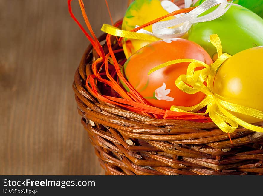 Colorful Easter eggs in basket on wooden background