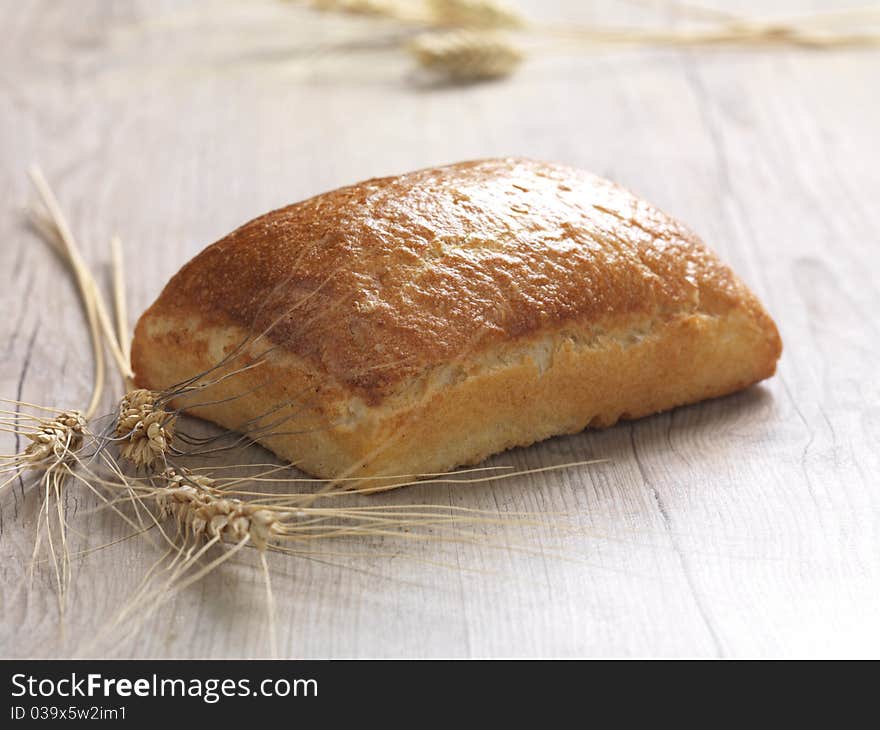 A close up of a baked bread on a wooden surface. A close up of a baked bread on a wooden surface