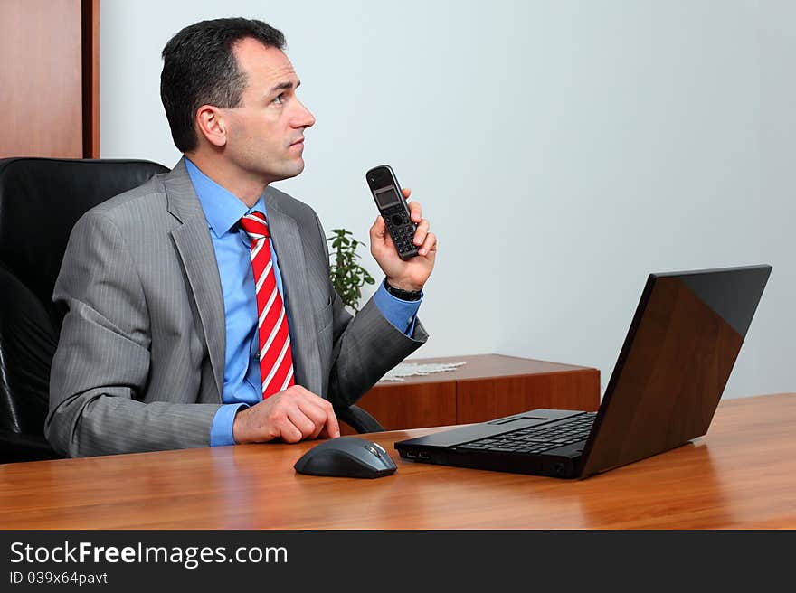 Handsome successful businessman in his office talk on the phone.