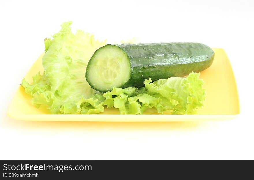 A green cucumber on the salad leaf on the white background