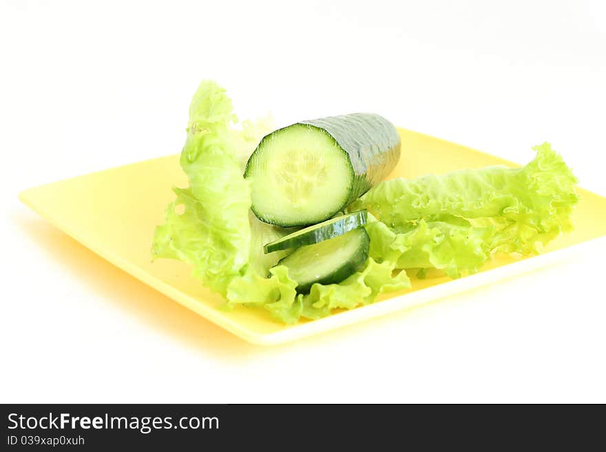 A green cucumber on the salad leaf on the white background