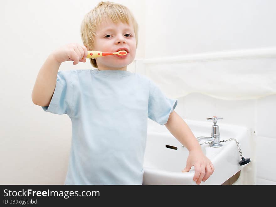 A toddler brushing his teeth in the bathroom at bedtime.