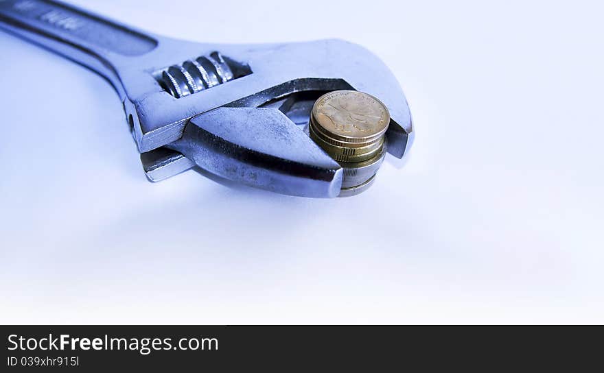 Adjustable wrench gripping a stack of coins with shallow depth of field. Adjustable wrench gripping a stack of coins with shallow depth of field.