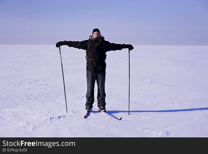 Cross-country skier standing on snow field in parallel to horizon