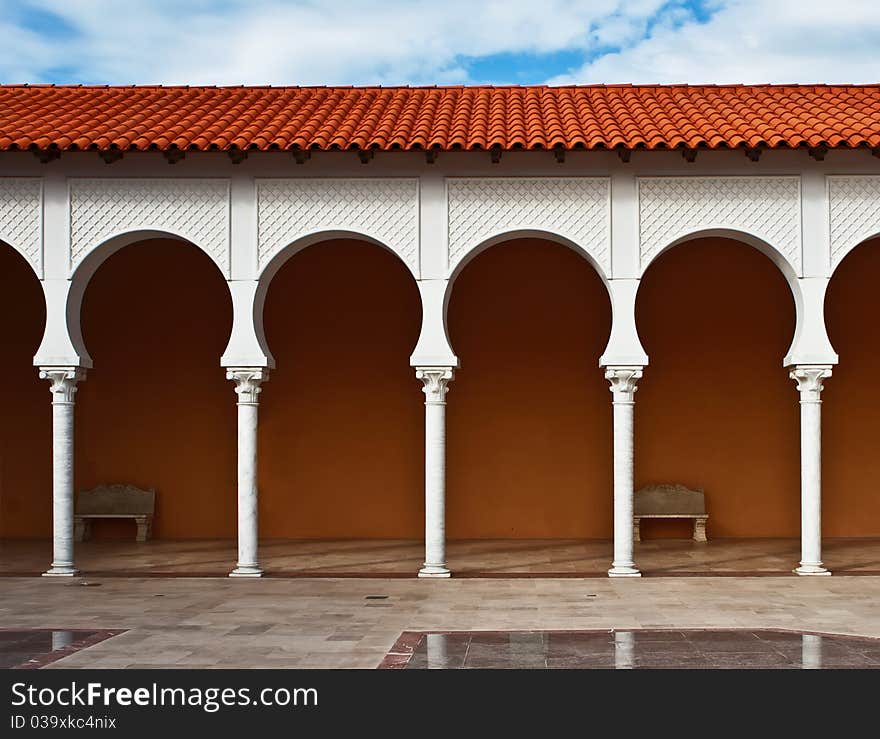 Pattern of a modern covered arcade with the tile roof on blue sky background.It is stylized to classical Spanish style. Caesarea, Israel. Pattern of a modern covered arcade with the tile roof on blue sky background.It is stylized to classical Spanish style. Caesarea, Israel.