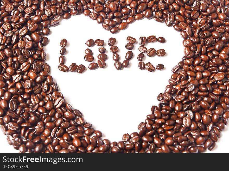 Heart from brown coffee beans and word of love on white background