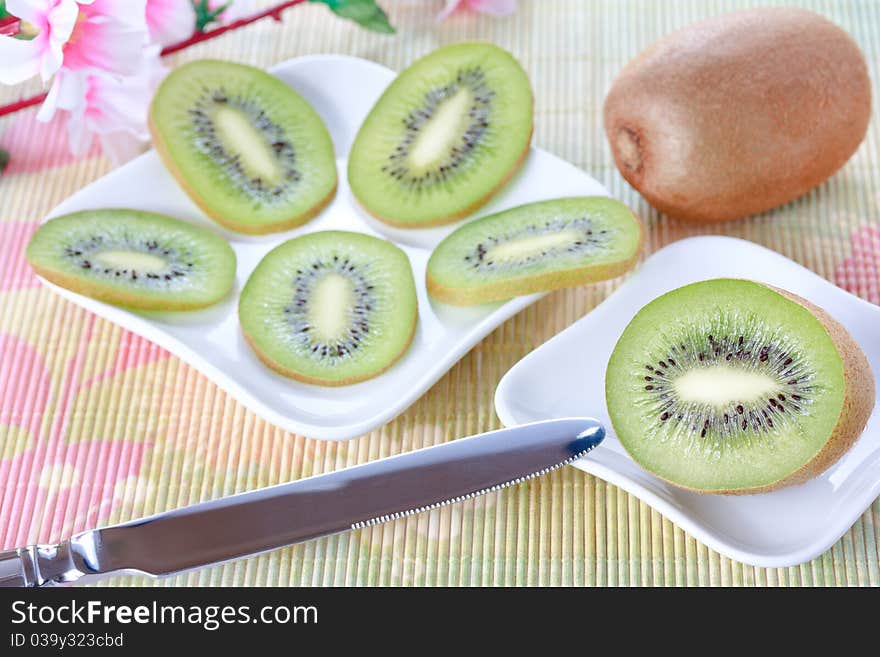 Ripe fresh kiwi slices on white shaped plates and knife. Ripe fresh kiwi slices on white shaped plates and knife