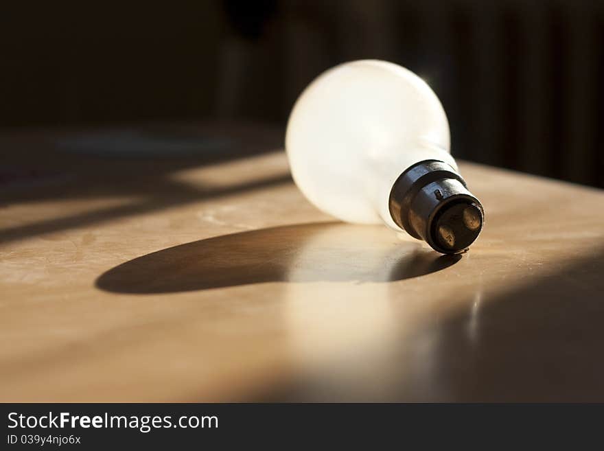 Standard 60w bayonet tungsten lightbulb laying in the sunlight. Standard 60w bayonet tungsten lightbulb laying in the sunlight