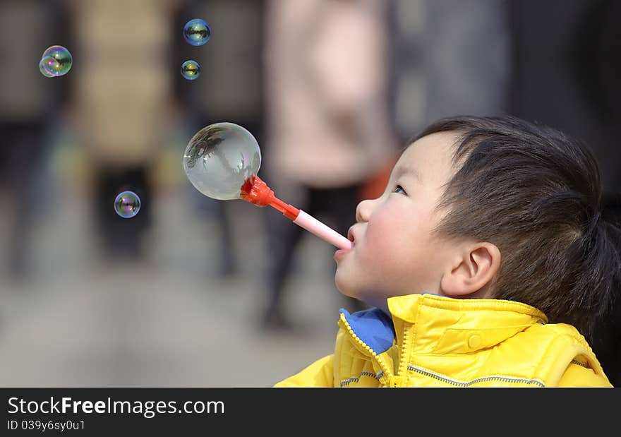 Child blowing soap bubbles in a park