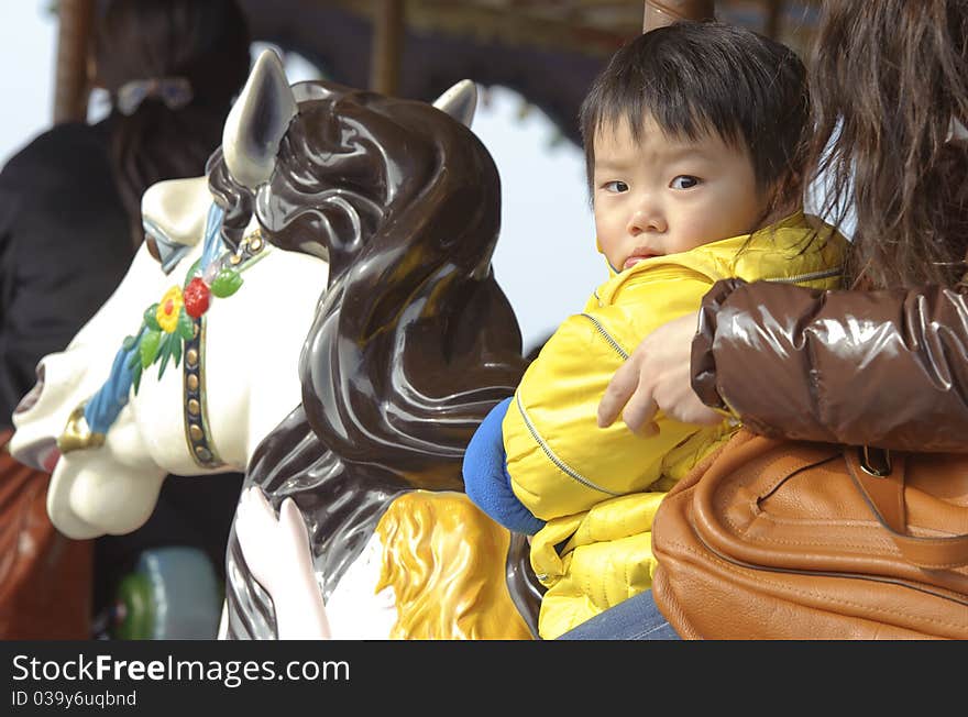 Baby riding merry go round in an amusement park. Baby riding merry go round in an amusement park