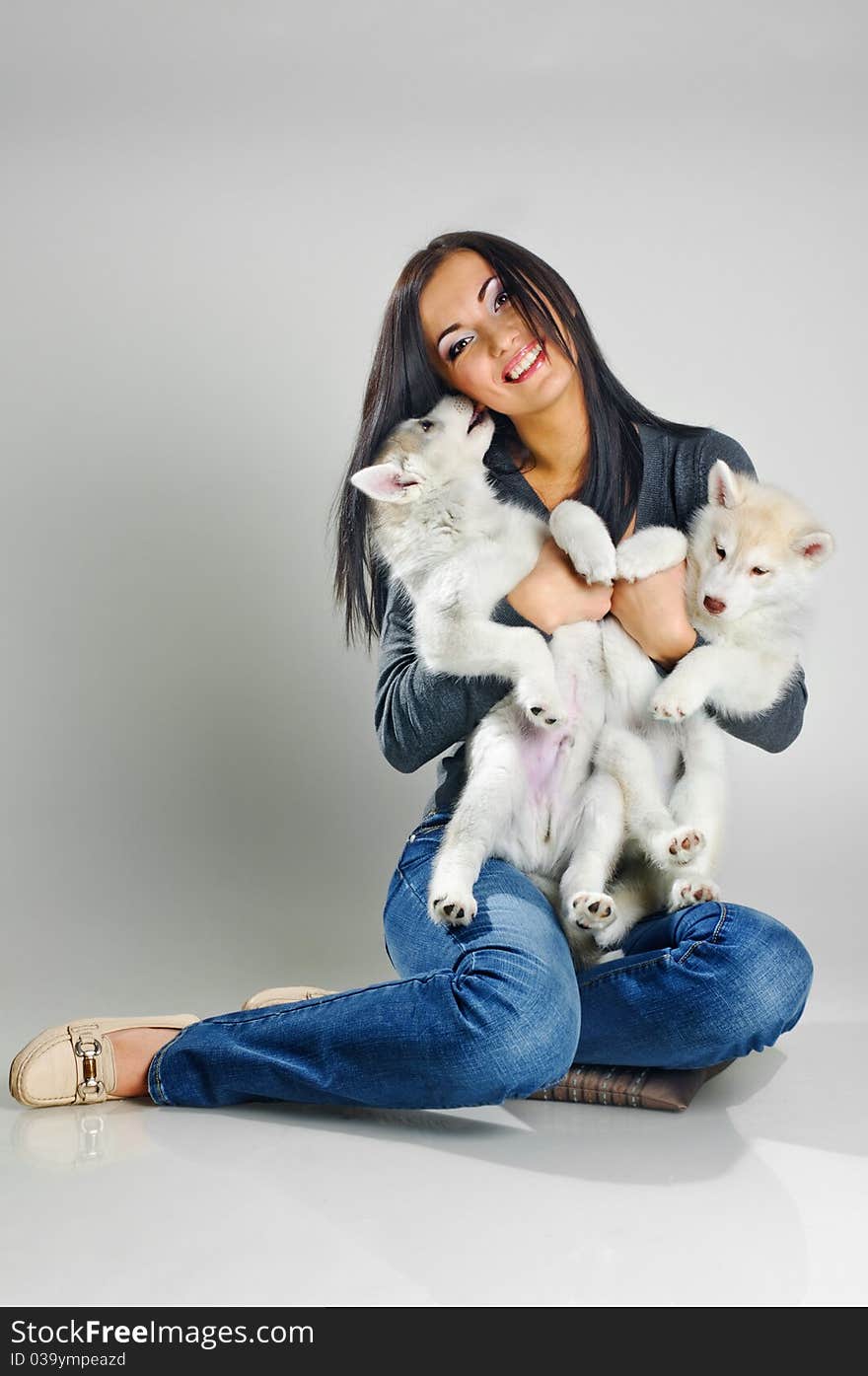 Playing woman with puppies of siberian haski on gray background. Playing woman with puppies of siberian haski on gray background