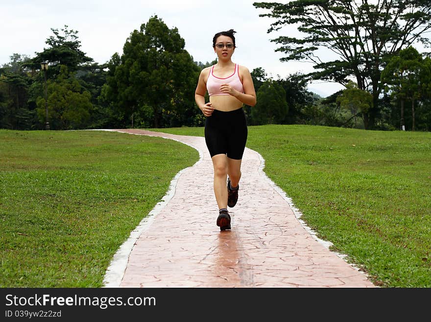 An Asian woman jogging at a park