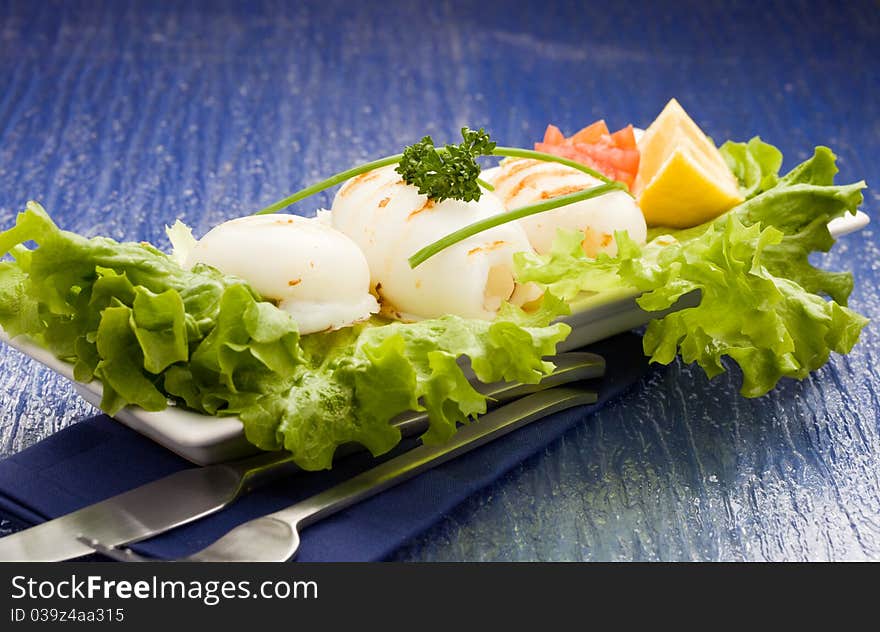 Squid with lettuce on blue glasstable