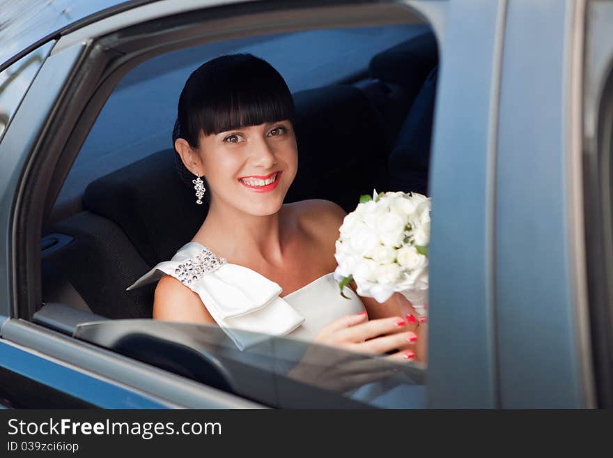 Happy bride with flower bouquet siting in the car. Happy bride with flower bouquet siting in the car