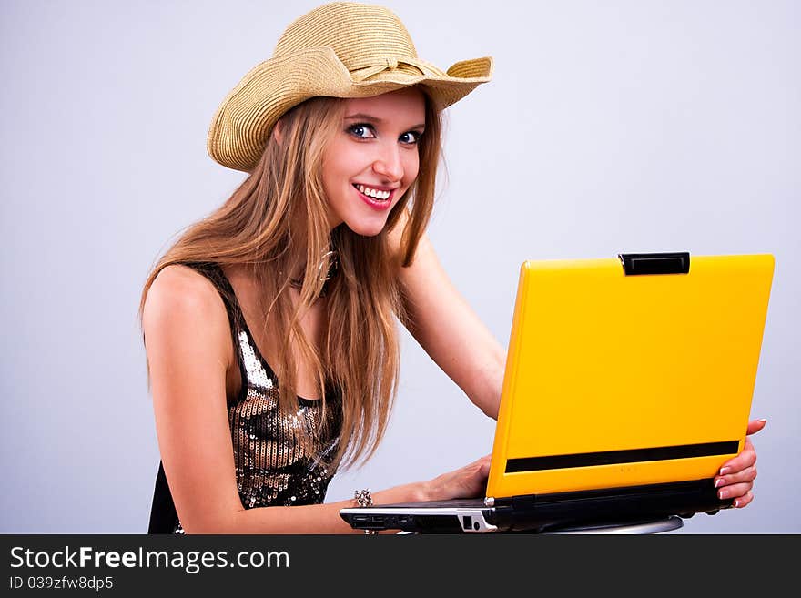 Attractive girl in a straw hat wth a yellow laptop