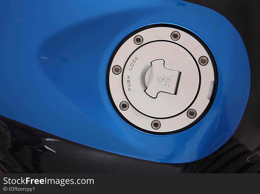 Blue and chrome fuel cap over black motorcycle. Blue and chrome fuel cap over black motorcycle