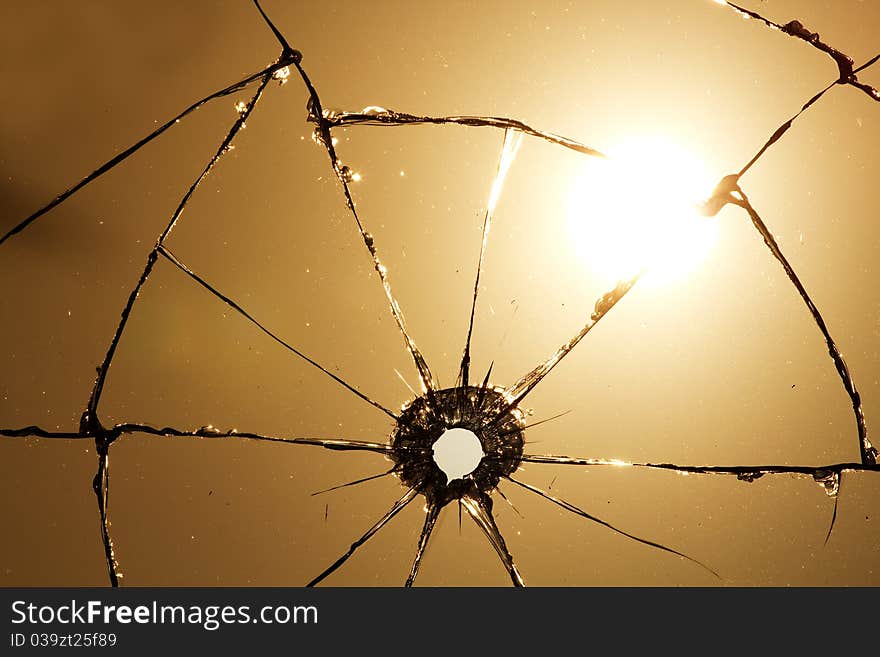 Hole and cracks in transparent glass after a shot against the sun. Hole and cracks in transparent glass after a shot against the sun