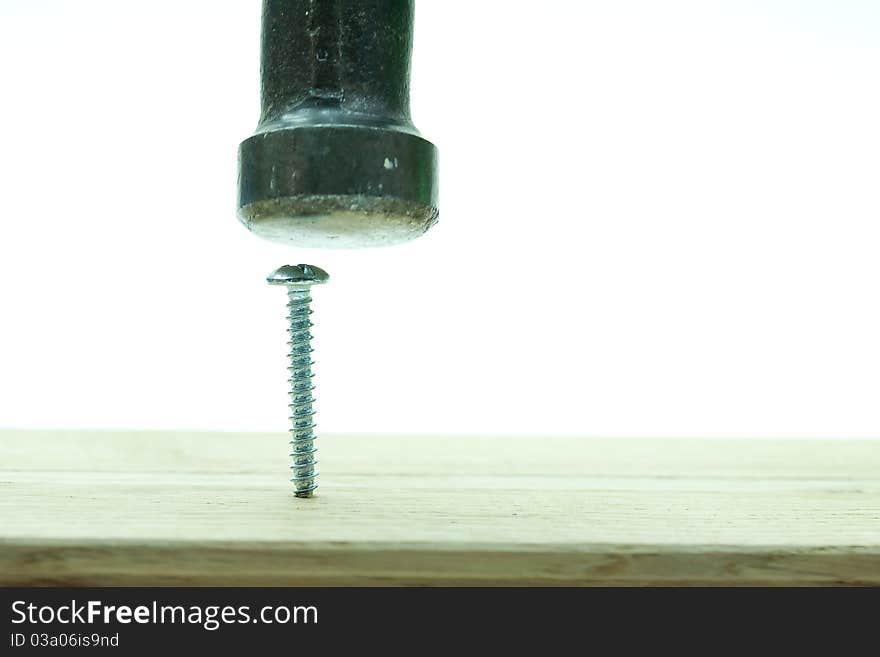 An old claw hammer with green handle is used to try in vain to hit a shiny silver colored into a wooden plank. An old claw hammer with green handle is used to try in vain to hit a shiny silver colored into a wooden plank.