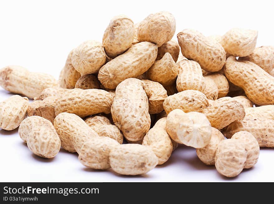 Raw peanuts with skin on a white background