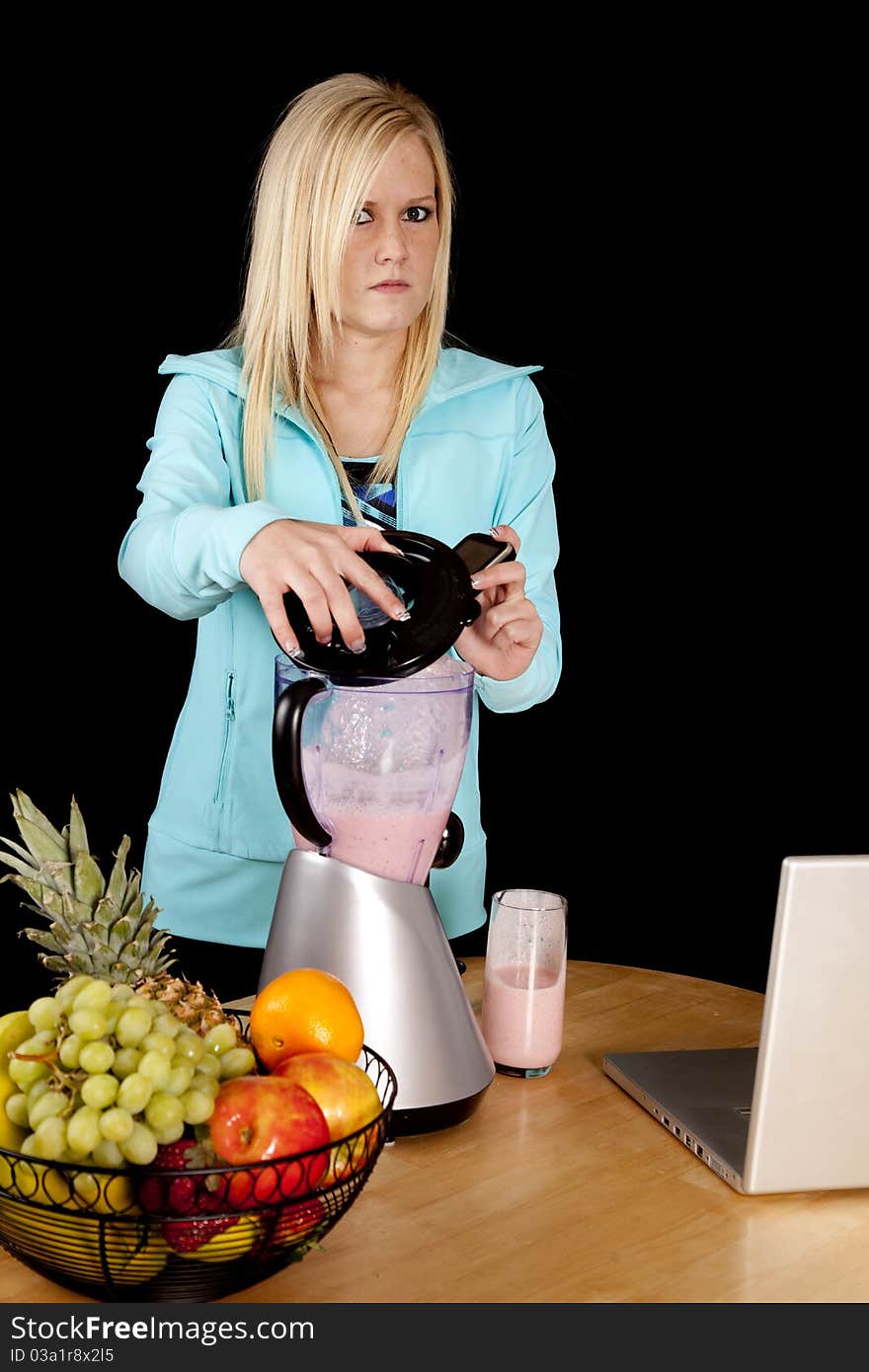 A woman is looking mad and dropping her cell phone into a blender. A woman is looking mad and dropping her cell phone into a blender.