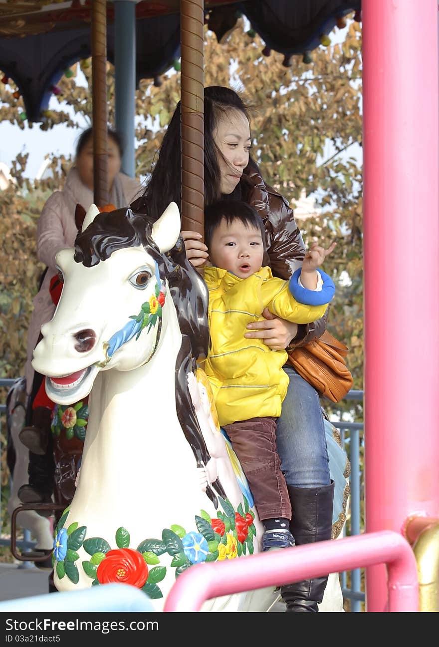 Baby riding merry go round in a park