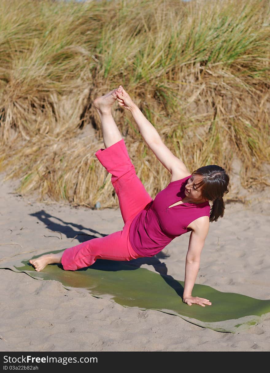 A young woman performs yoga on a beach. A young woman performs yoga on a beach.