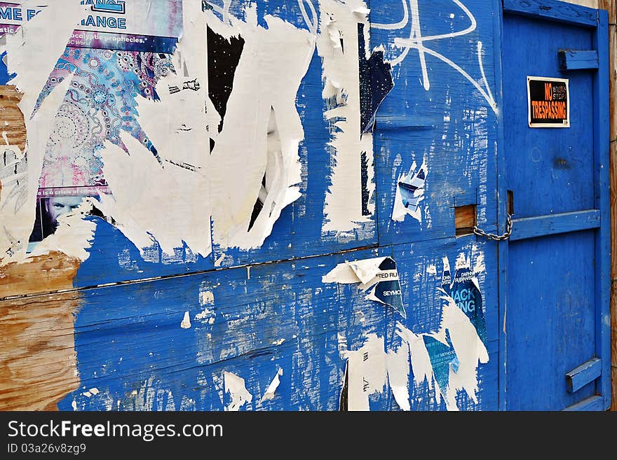 Blue wall with layers of ripped posters and a no trespassing sign on the door. Blue wall with layers of ripped posters and a no trespassing sign on the door