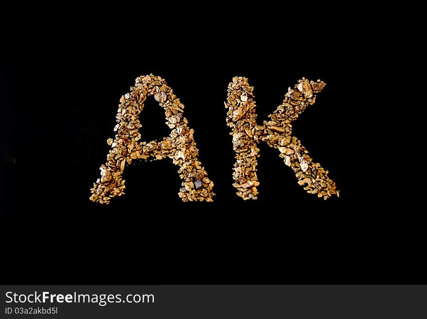 AK spelt with real Alaskan Gold on a black background from Nome. AK spelt with real Alaskan Gold on a black background from Nome