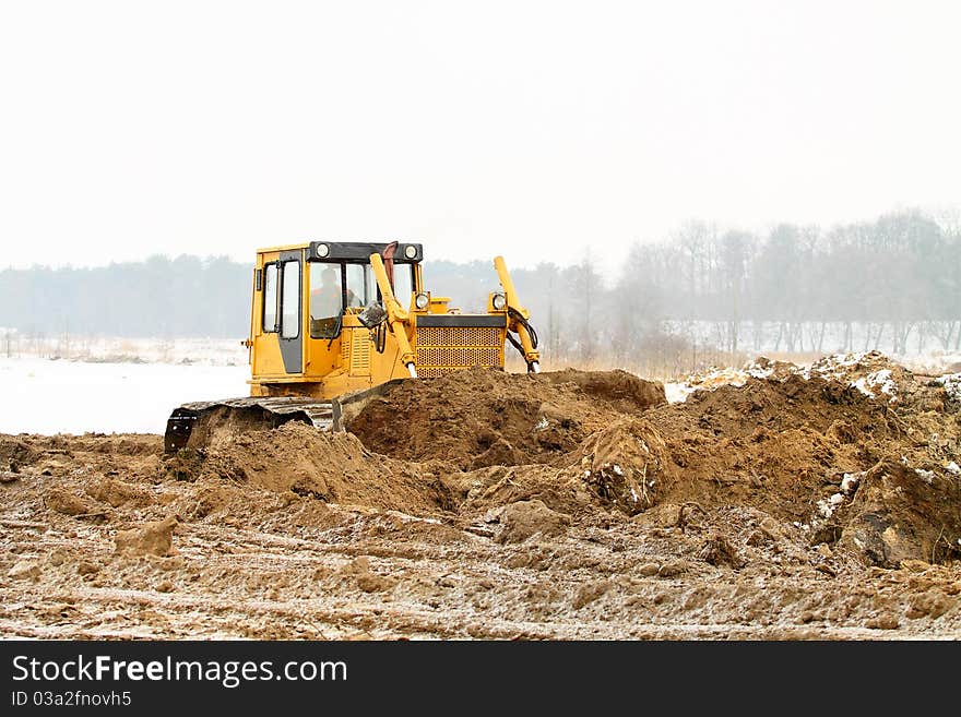 A yellow bulldozer working in the winter