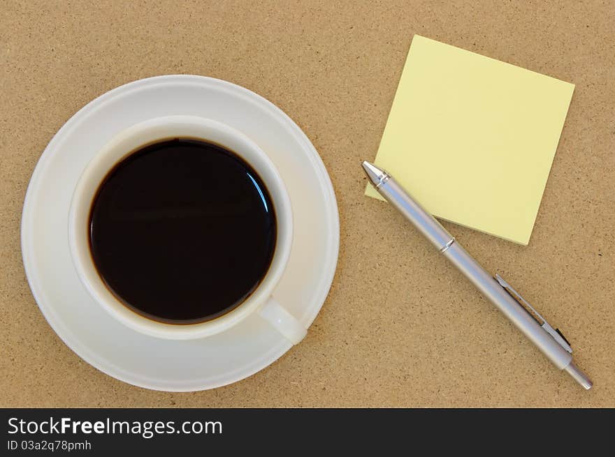 Blank postit note and pen on table arranged with cup of coffee. Blank postit note and pen on table arranged with cup of coffee