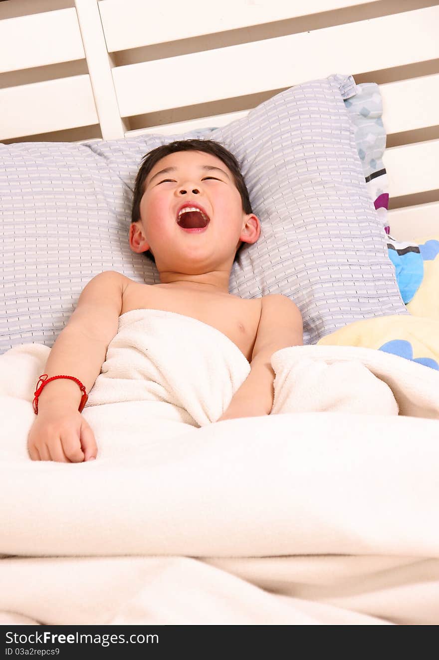 Picture of a little chinese boy laughing happily while lying on the bed. Picture of a little chinese boy laughing happily while lying on the bed