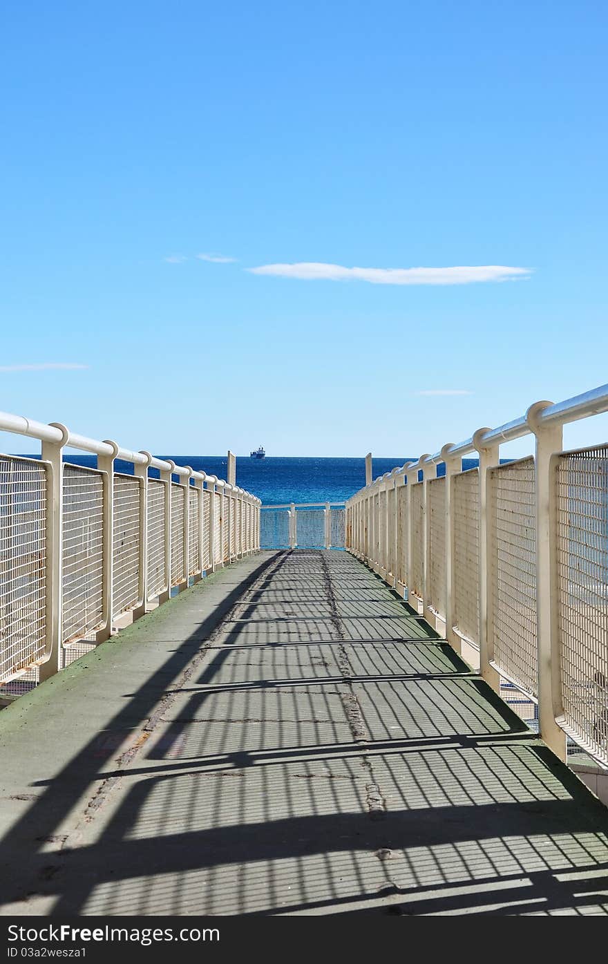 Iron pier to coast of Alicante with cargo ship, Spain