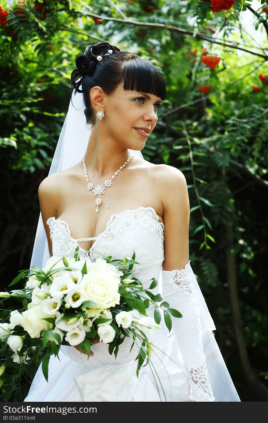 Beautiful bride woman with guelder rose on the background outdoors