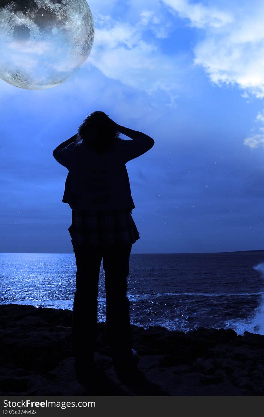 A sad lone woman with full moon on a cliff edge