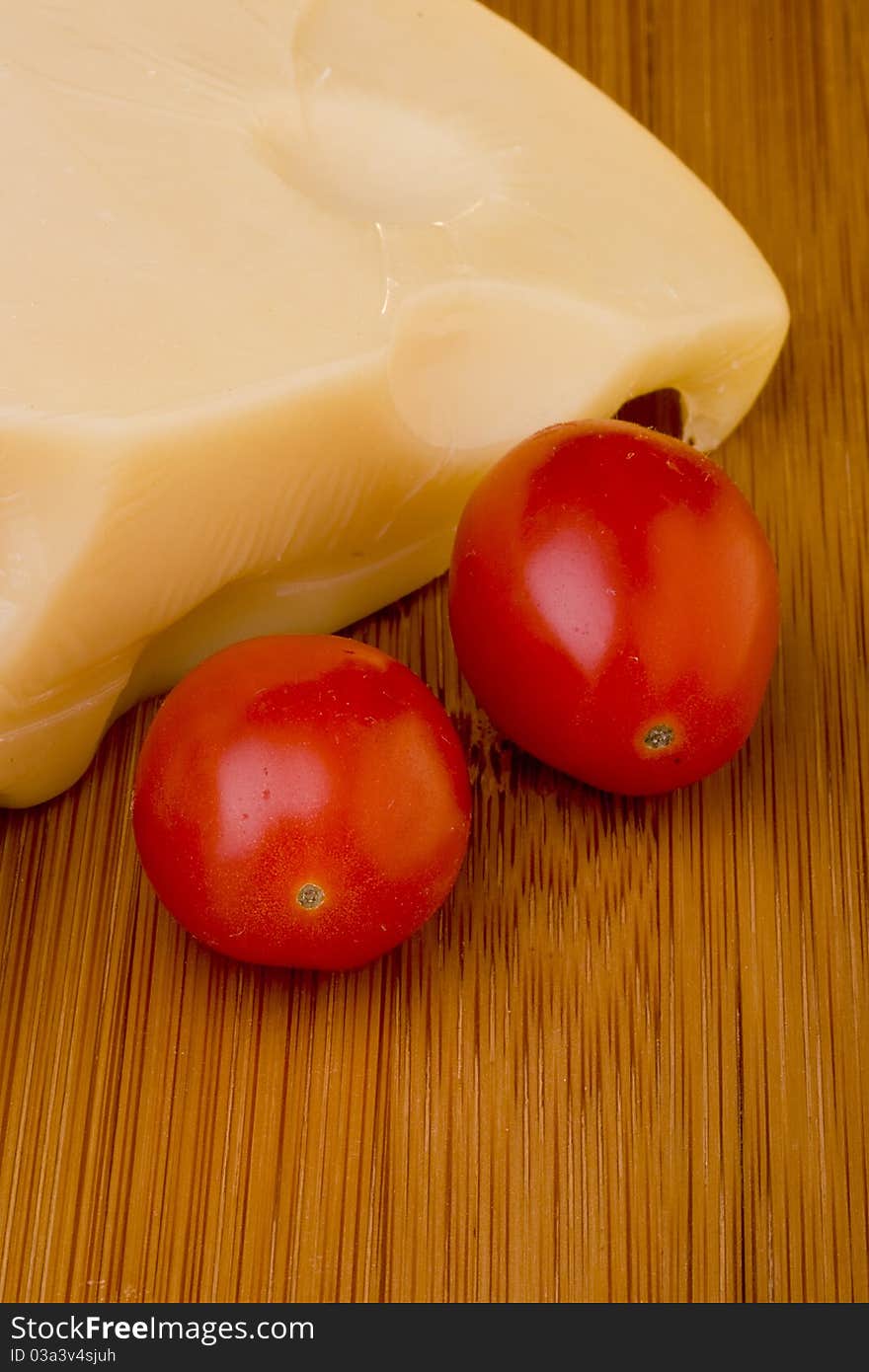 Swiss cheese slice and red tomato on a wood desk.