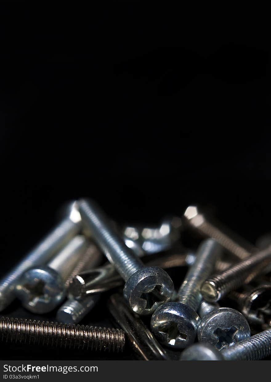 Metallic screws on black background, used as poster. Metallic screws on black background, used as poster