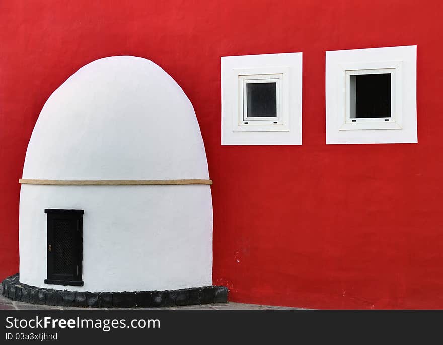 A Spanish porch, door, and two windows on a richly coloured red wall. A Spanish porch, door, and two windows on a richly coloured red wall