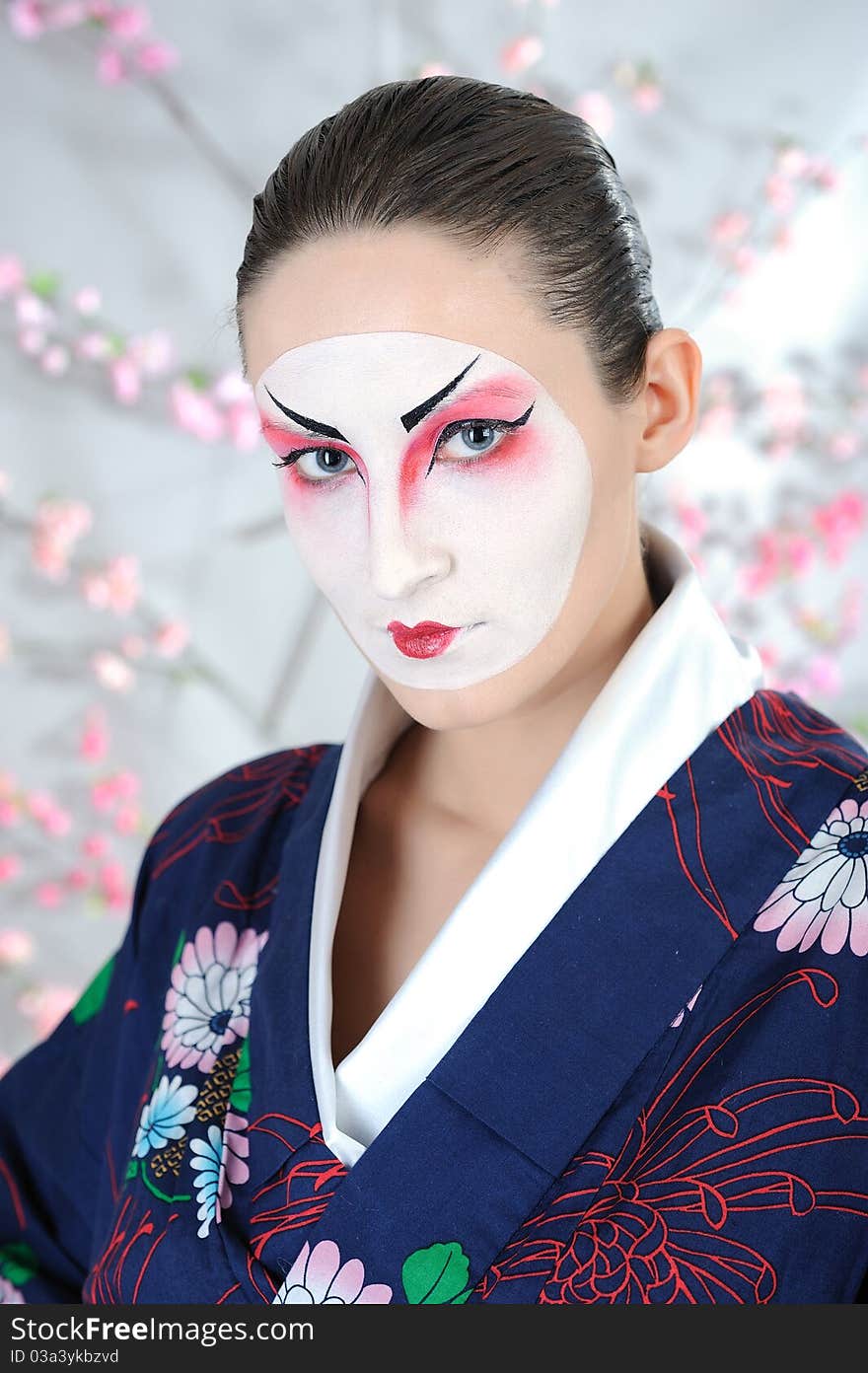 Artistic portrait of japan geisha woman with creative make-up near sakura tree