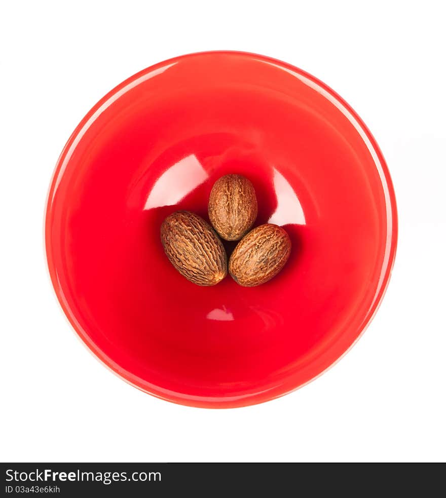 Red plate with nutmeg isolated on a white background