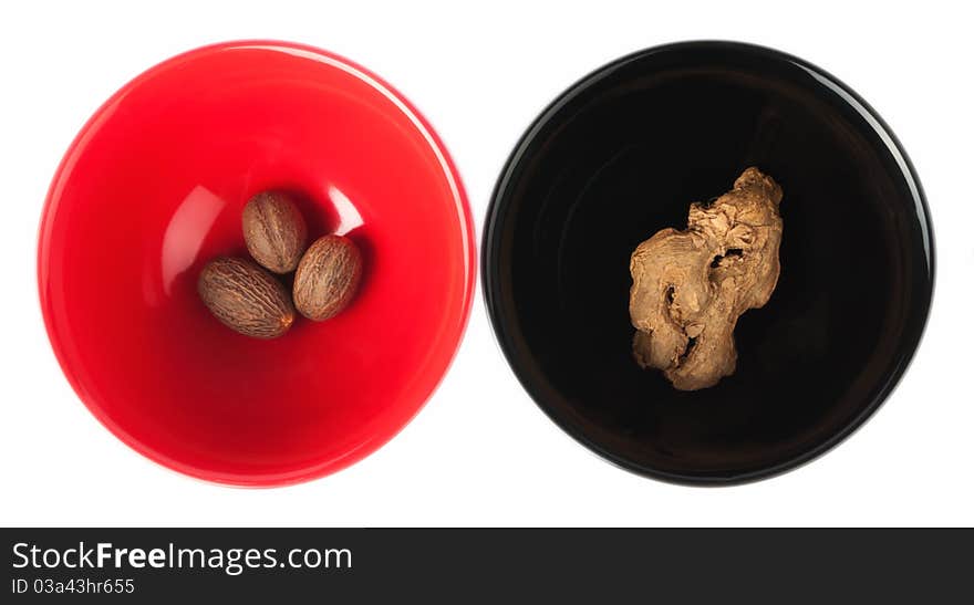 Red and black dish with spices, nutmeg and ginger,white background