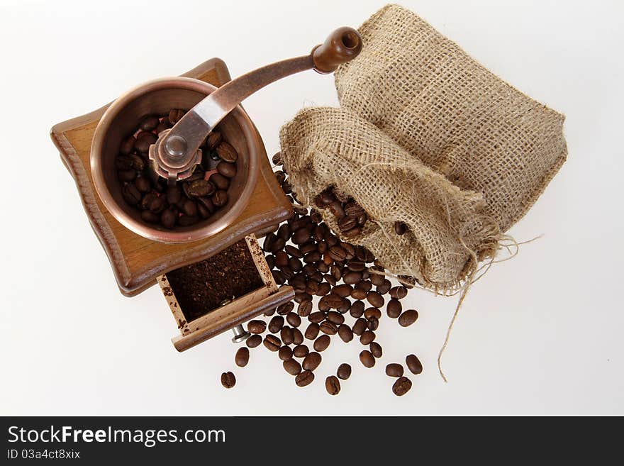 Coffee mill with burlap sack of roasted beans on the white background