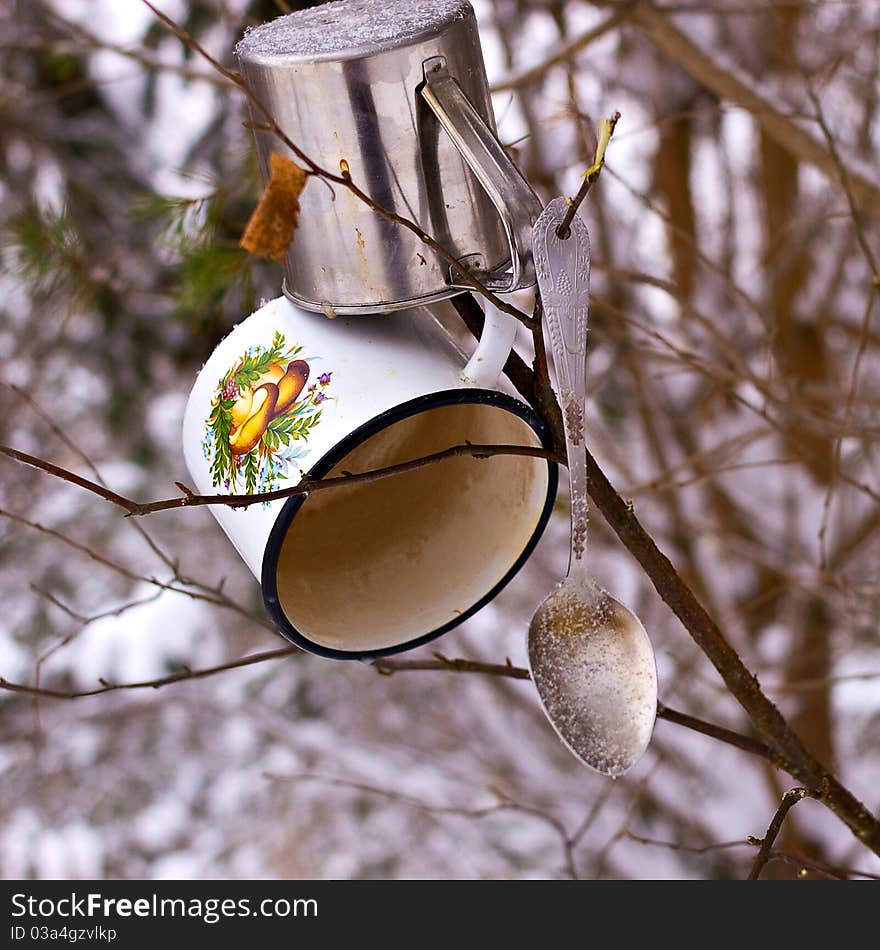 On a tree branch hanging iron mugs - tourists going to drink tea. On a tree branch hanging iron mugs - tourists going to drink tea